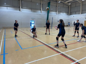 Image shows volleyball game with the ball in mid air