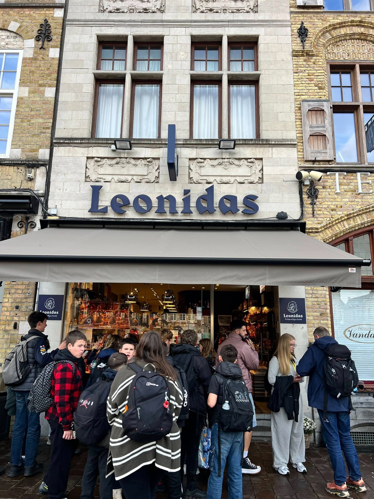 A group of pupils from the College gathering excitedly outside the Leonidas chocolate shop in Ypres during their Year 8 trip to Belgium.