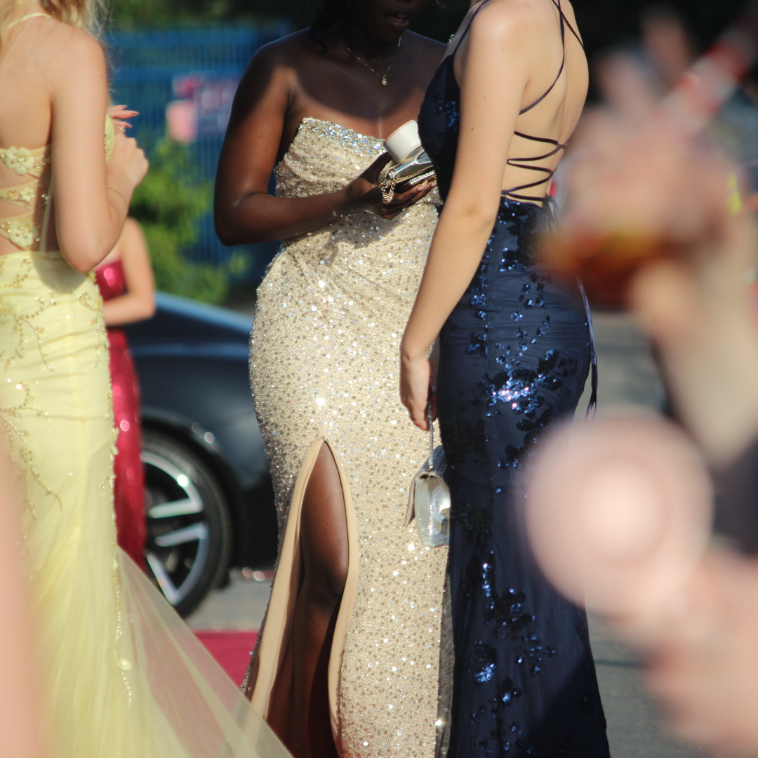 Pupils in formal dresses talking together outdoors during the prom arrival.