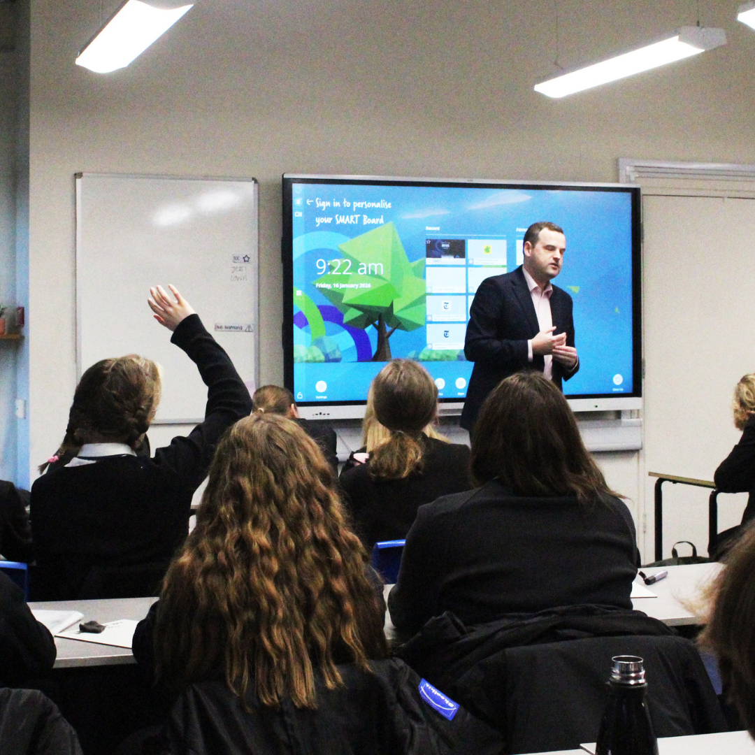 Guest speaker leading a classroom session while pupils listen and ask questions.