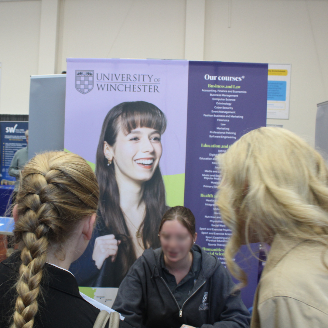 Pupils speaking with a representative at the University of Winchester display stand during a careers event.