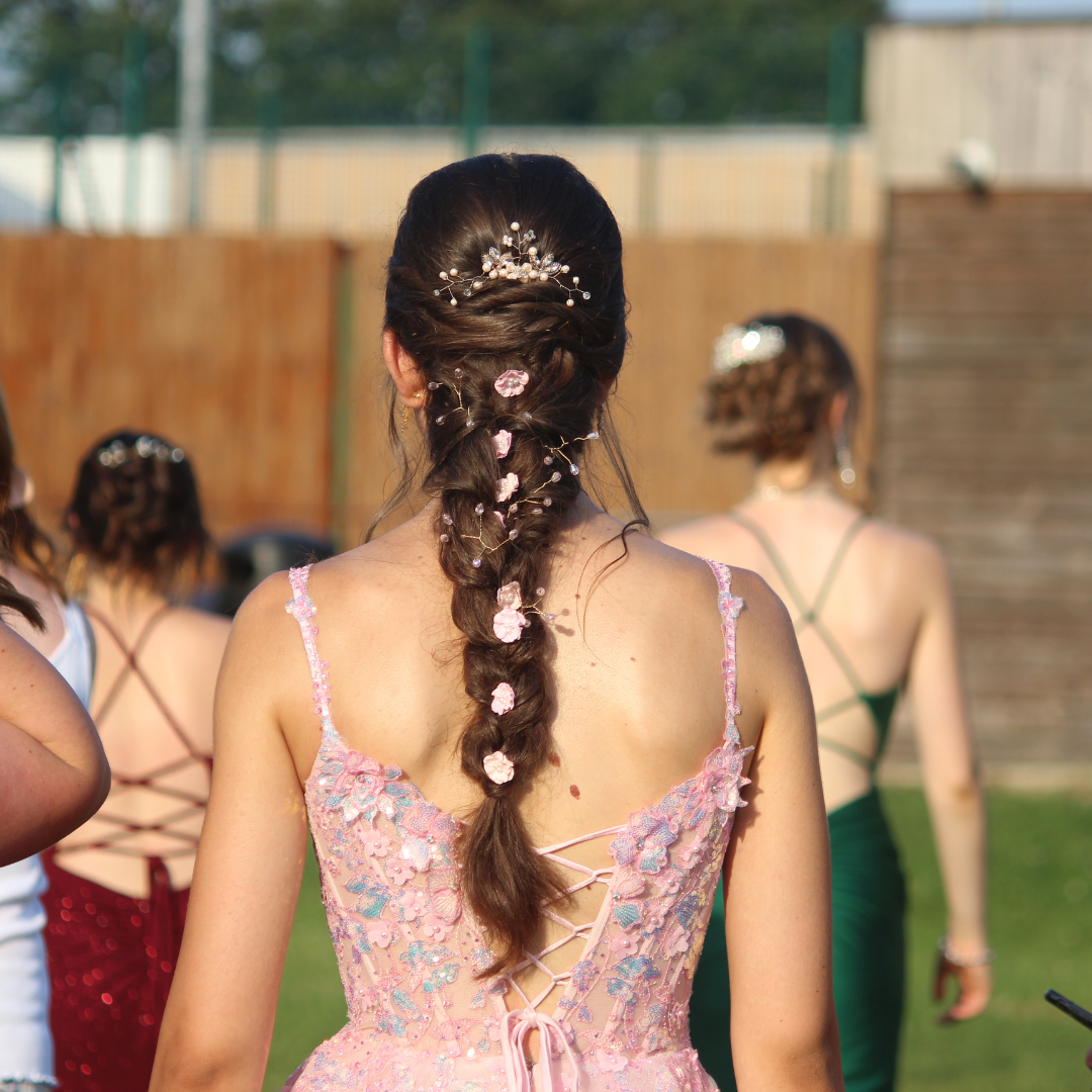 Rear view of a pupil with braided hair decorated with pink flowers and hair accessories.