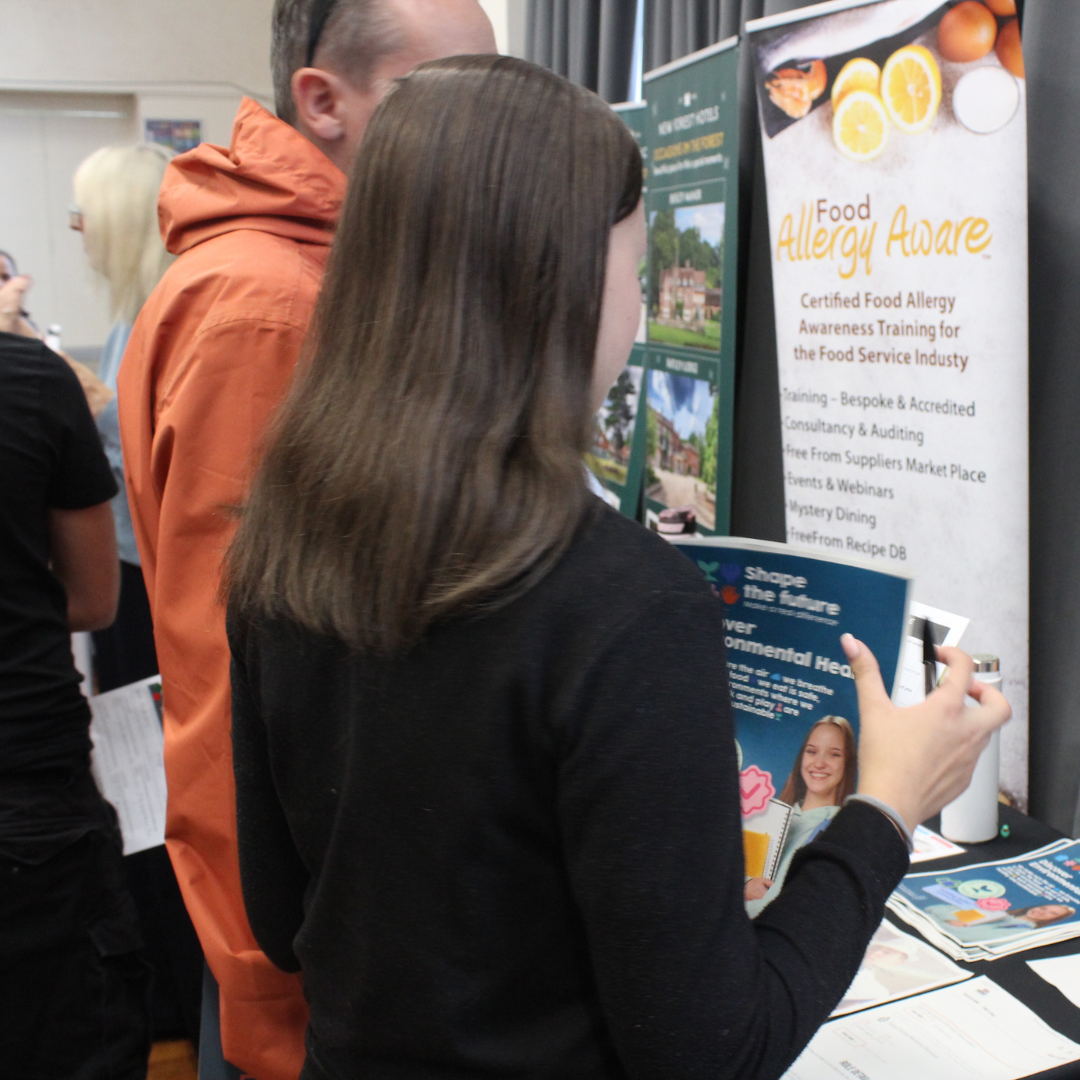 A pupil holding an environmental health brochure at the Food Allergy Aware stand.