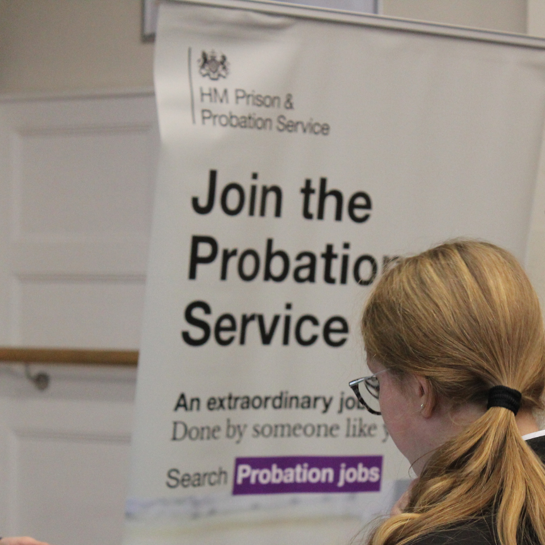 A pupil reading information on a display banner for HM Prison plus Probation Service.