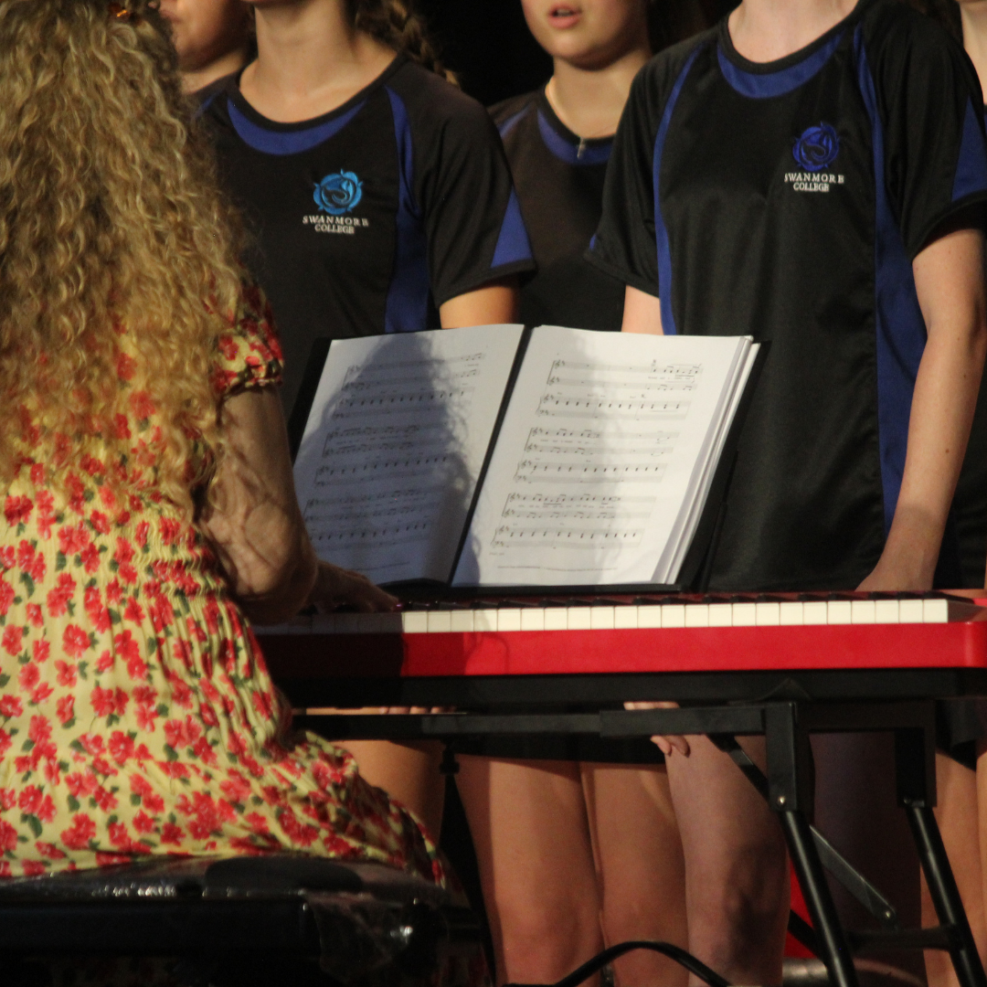 Image shows a close up of pupils singing in a choir being accompanied by a pianist