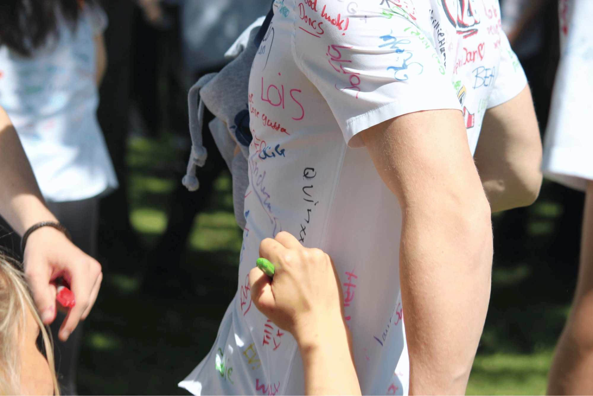 Close-up of a pupil signing a classmate's shirt during Year 11 leavers' celebrations.