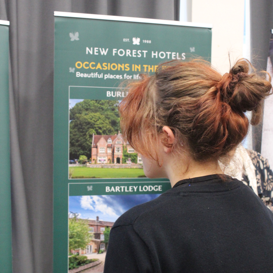 A pupil looking closely at an information banner for New Forest Hotels.