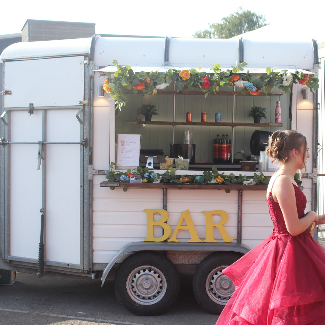 Decorated mobile bar with floral garlands and a pupil walking past.