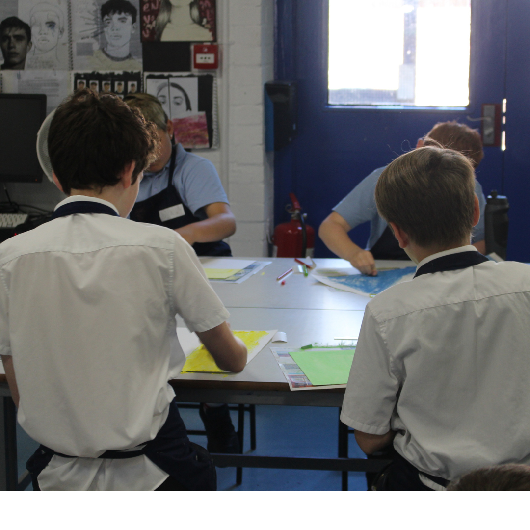 Image shows four pupils sitting at a table working on pieces of artwork.