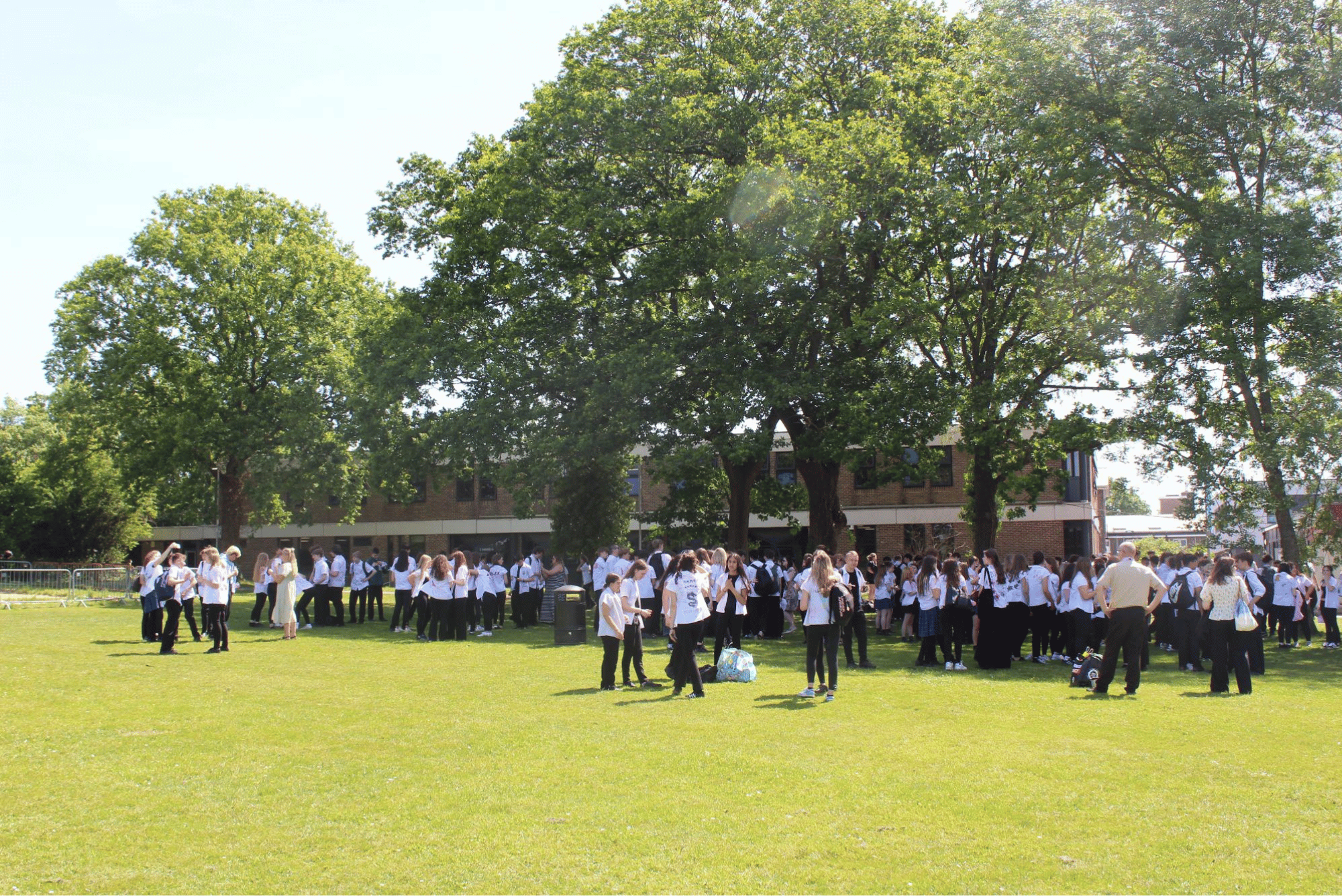 Wide view of Year 11 pupils gathered on the College field for leavers' day celebrations and farewells.