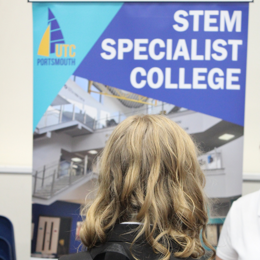 A pupil viewed from behind looking at a promotional banner for UTC Portsmouth, a STEM Specialist College.