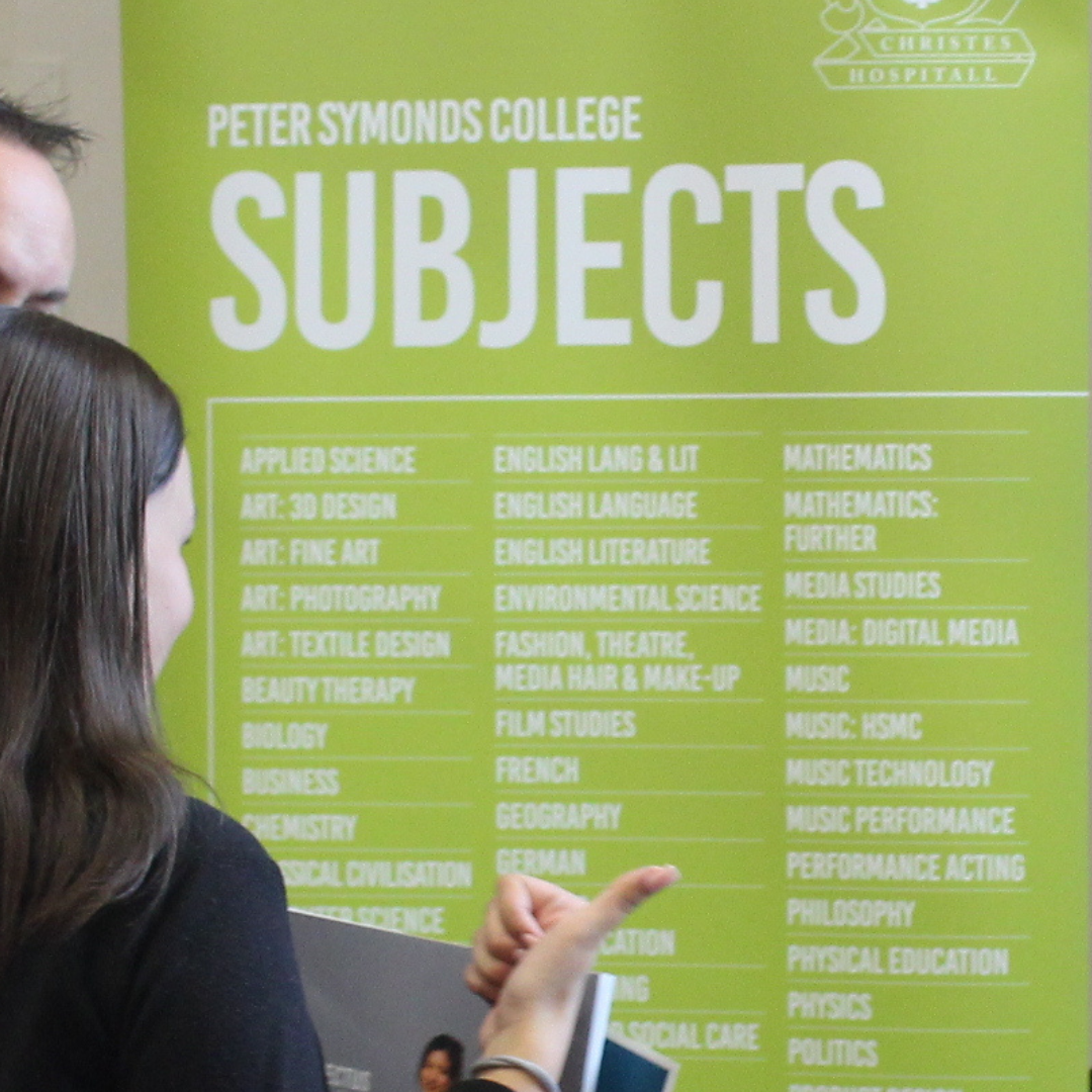 pupil pointing to subject options on a Peter Symonds College exhibition banner.