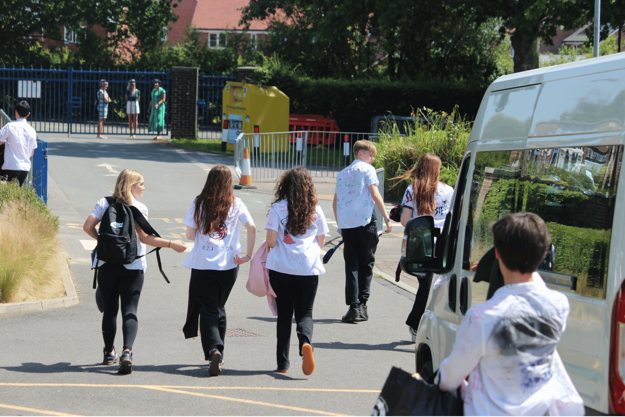 Group of Year 11 pupils walking away from the College after their final day, carrying bags and shirts covered in messages.