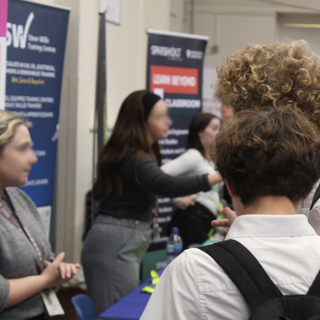Pupils engaging with representatives at exhibition stands during a careers event.