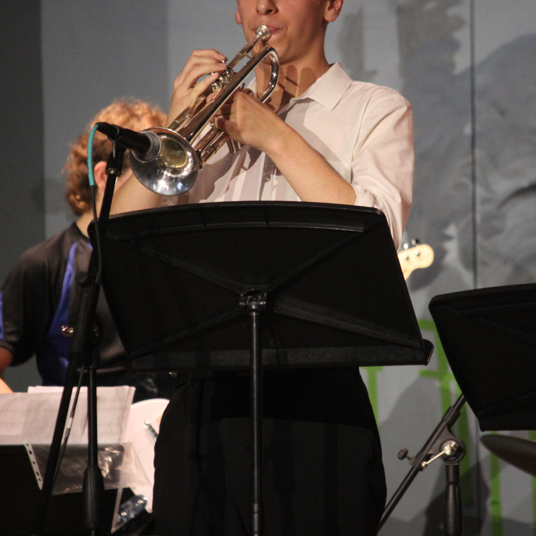 image shows a pupil playing the trumpet on stage