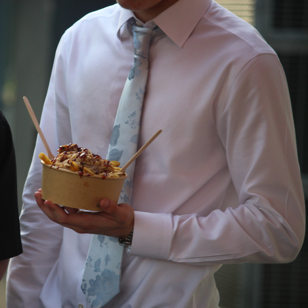 Pupil holding a takeaway food tray while wearing a white shirt and patterned tie.
