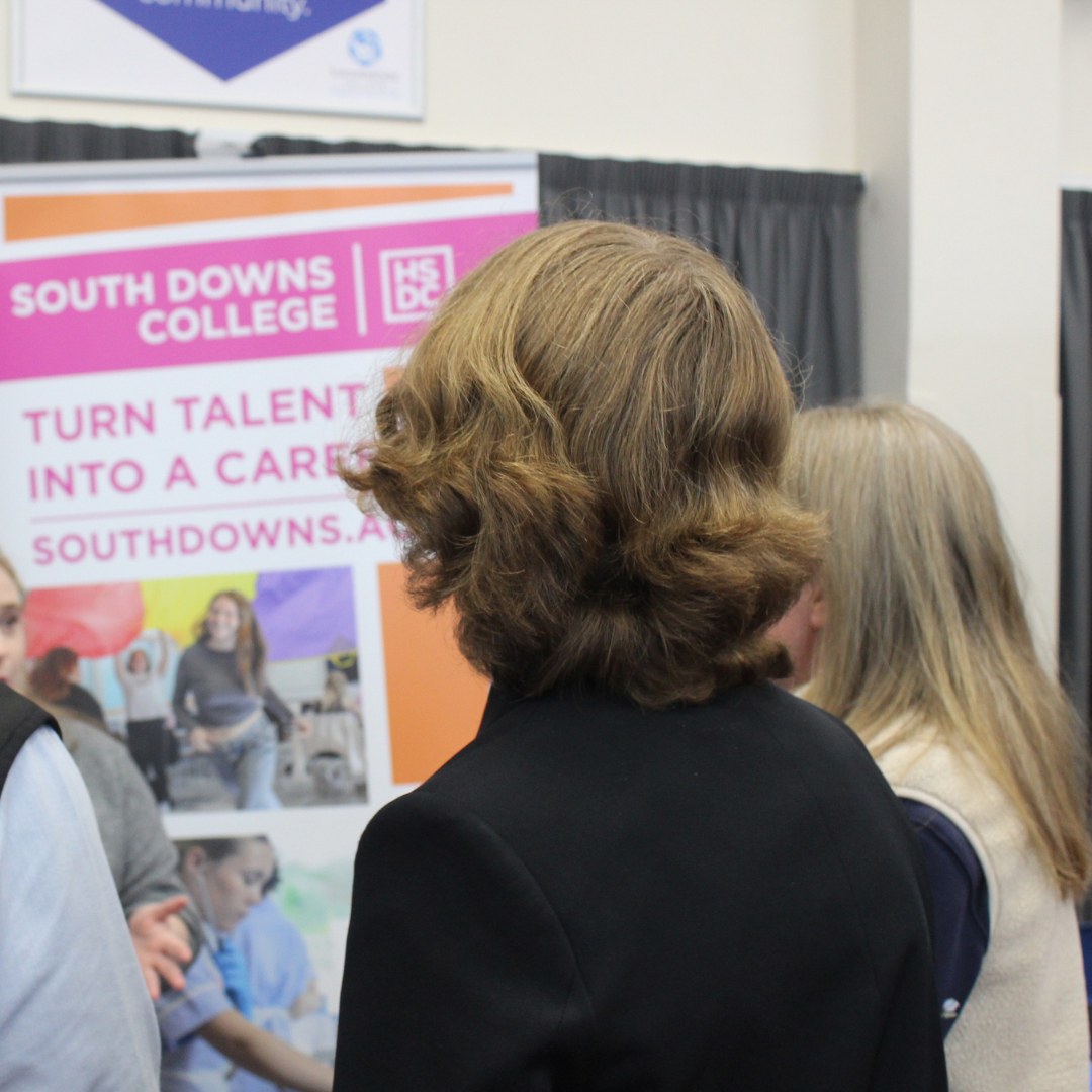 Pupils gathering in front of a South Downs College promotional stand.