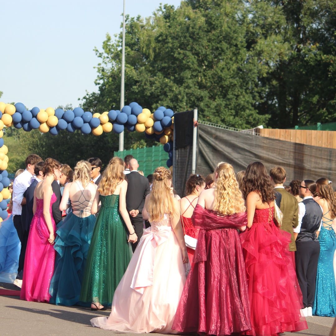 Pupils gathered beneath a blue and gold balloon arch at the prom entrance.