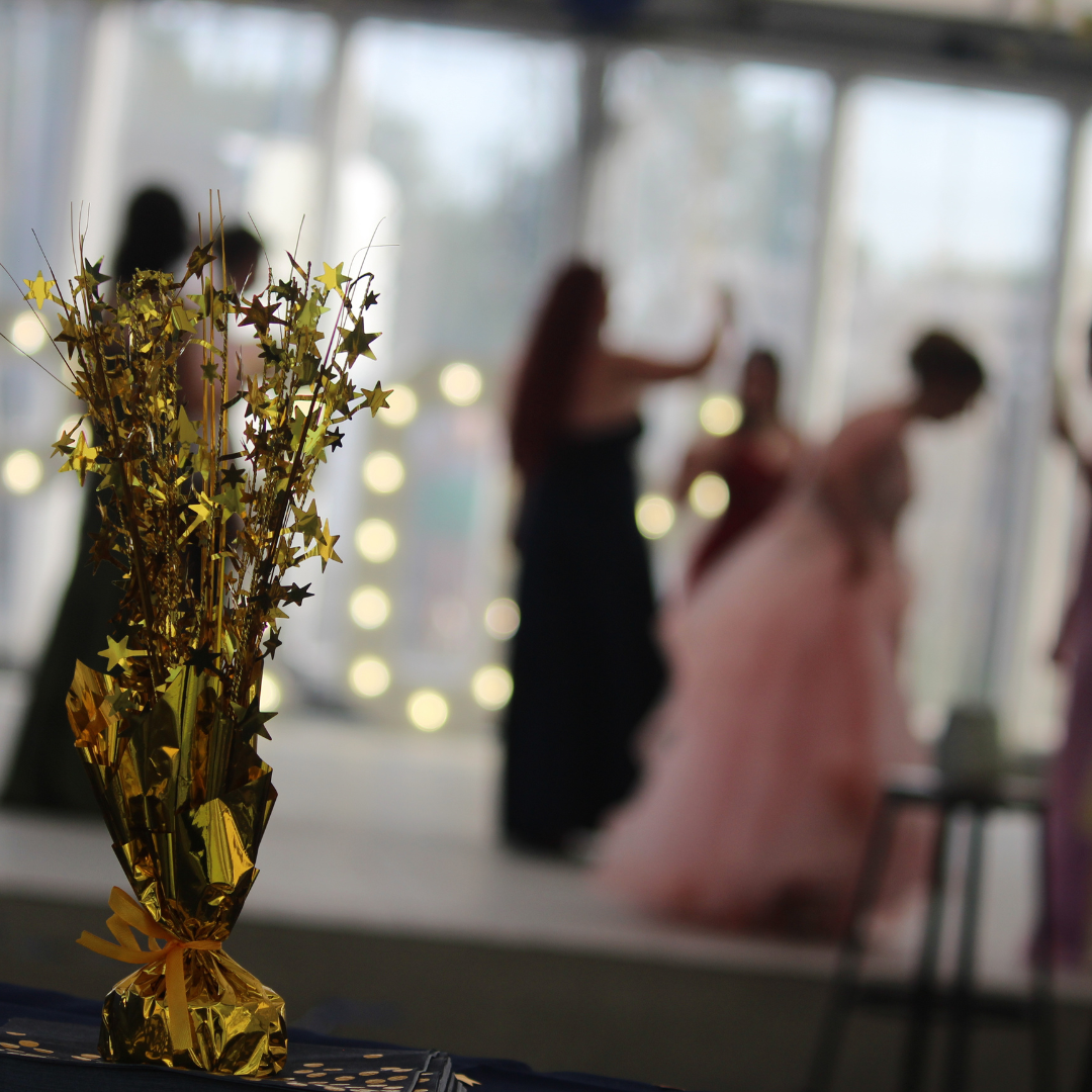 Gold star table decoration with pupils inside the prom venue in the background.