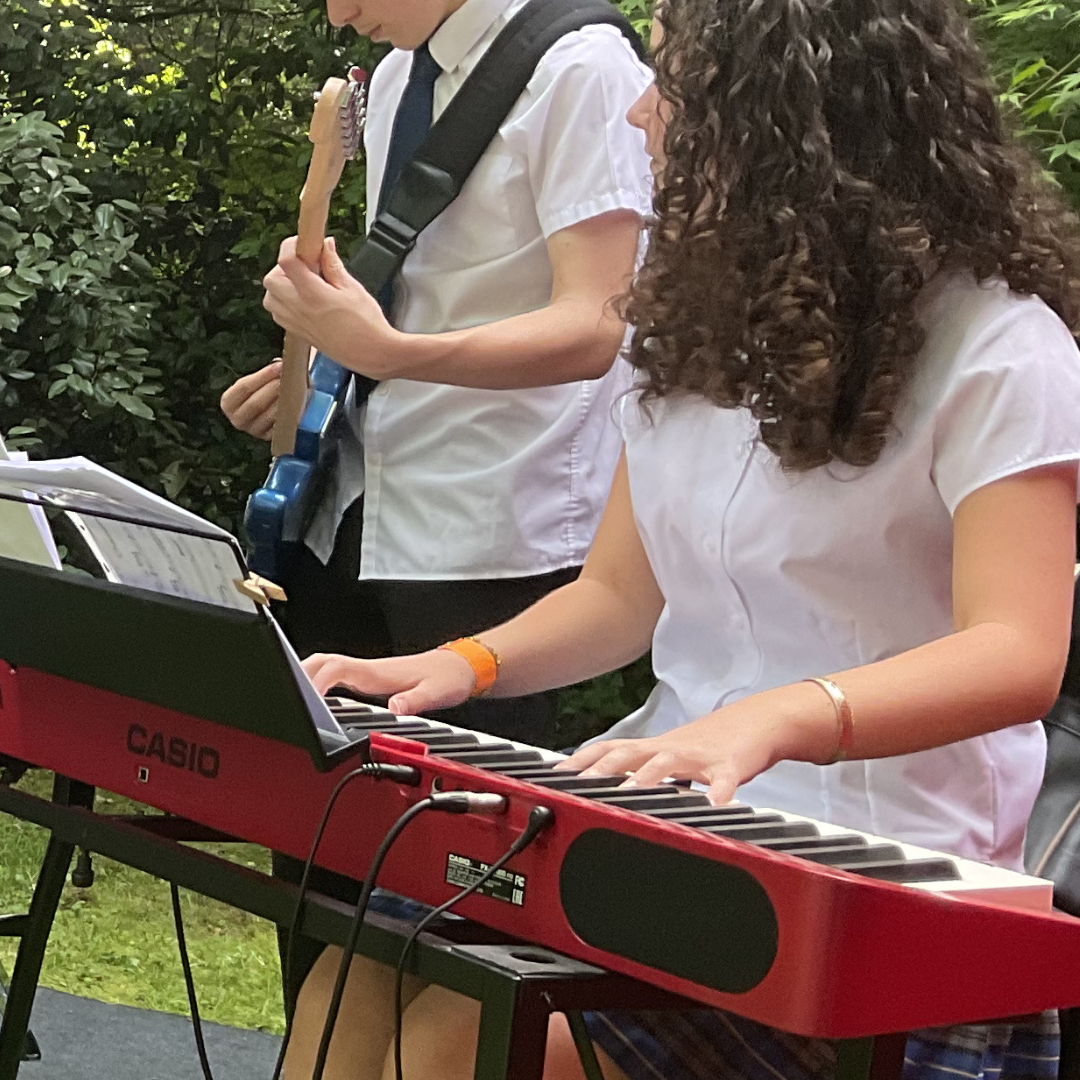 Close-up of a pupil playing a red keyboard during the jazz ensemble's outdoor performance.