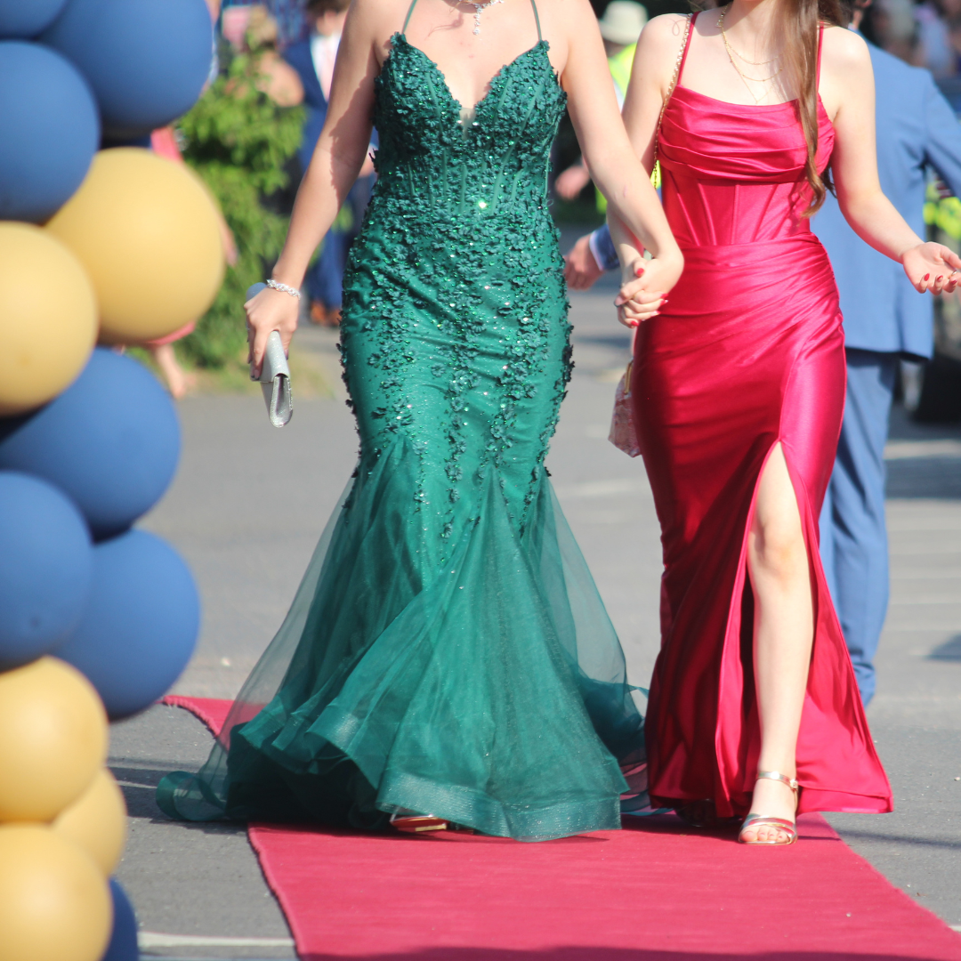 Two pupils holding hands while walking along the red carpet.