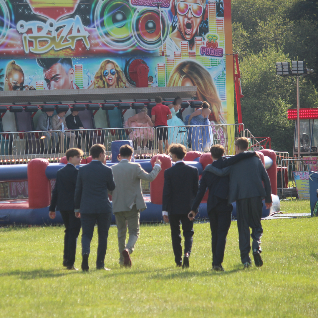 Group of pupils walking across the field towards the fairground rides.