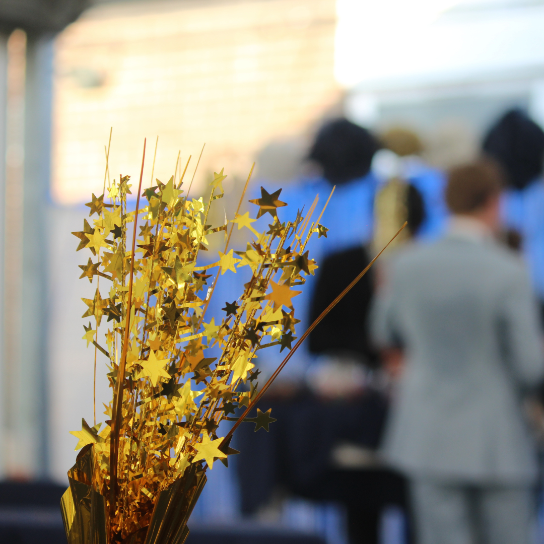 Gold star table decoration with pupils inside the prom venue in the background.