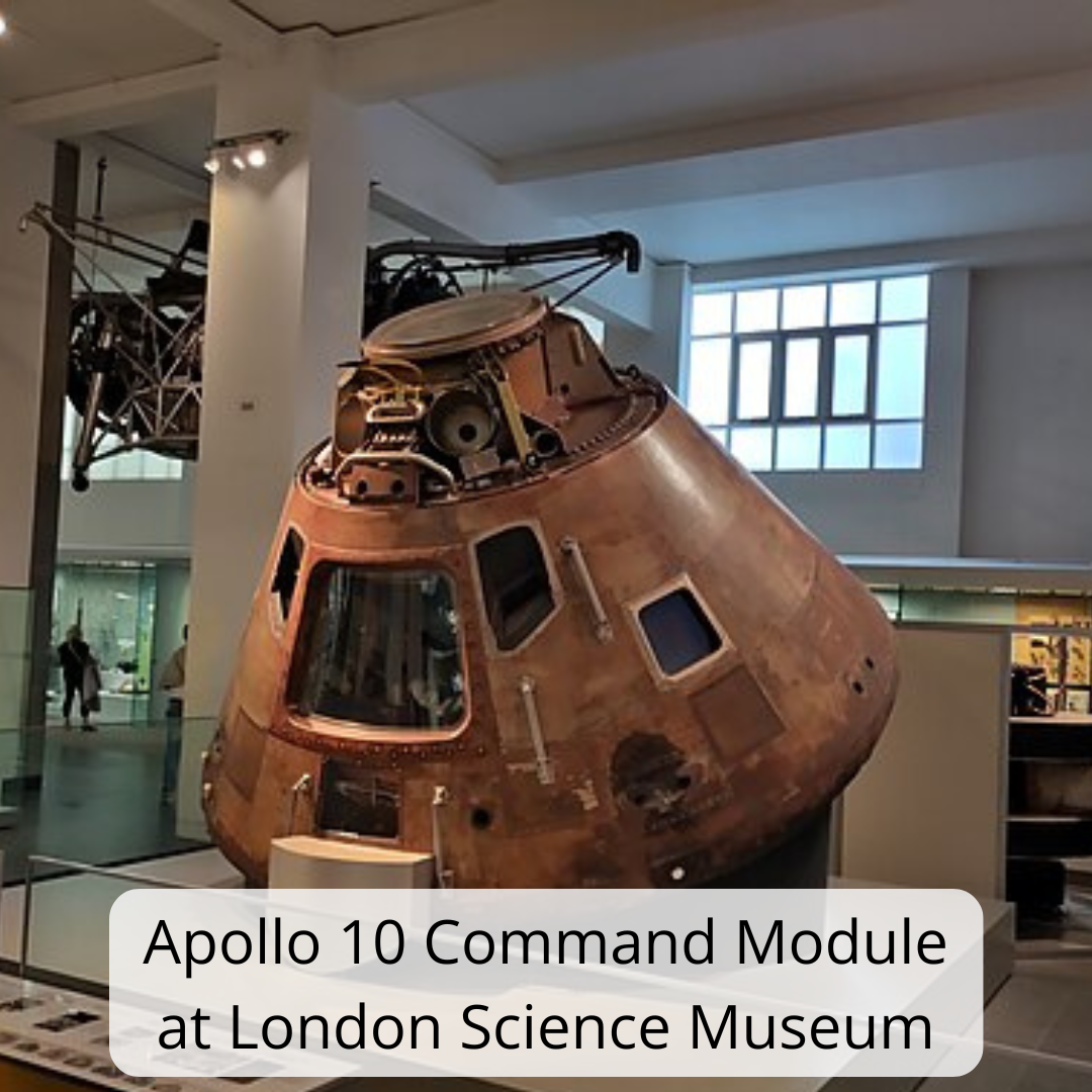 Image shows the Apollo 10 Command Module displayed inside the Science Museum in London. The spacecraft is cone-shaped and covered in heat-scorched copper-brown metal, showing marks and wear from space travel and re-entry. Small square and trapezoid windows are visible around the upper section, along with panels, bolts, and technical components. The module is positioned indoors within a bright museum gallery, with white pillars, display cases, and large windows in the background.