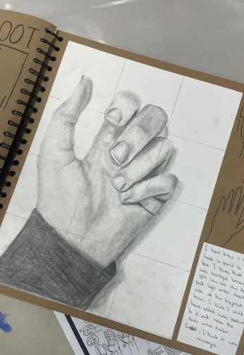A detailed pencil drawing of a hand in a sketchbook, showing careful shading, proportion, and observation work.