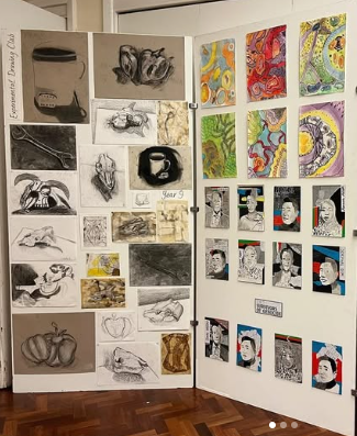 A display board showing a collection of pupil artwork, including observational drawings, mixed media studies, and colourful abstract pieces arranged in a school exhibition space.