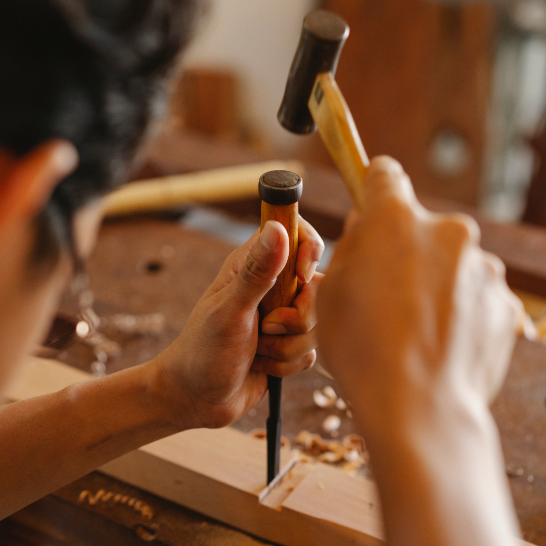 Image shows someone using a hammer and chisel in woodwork