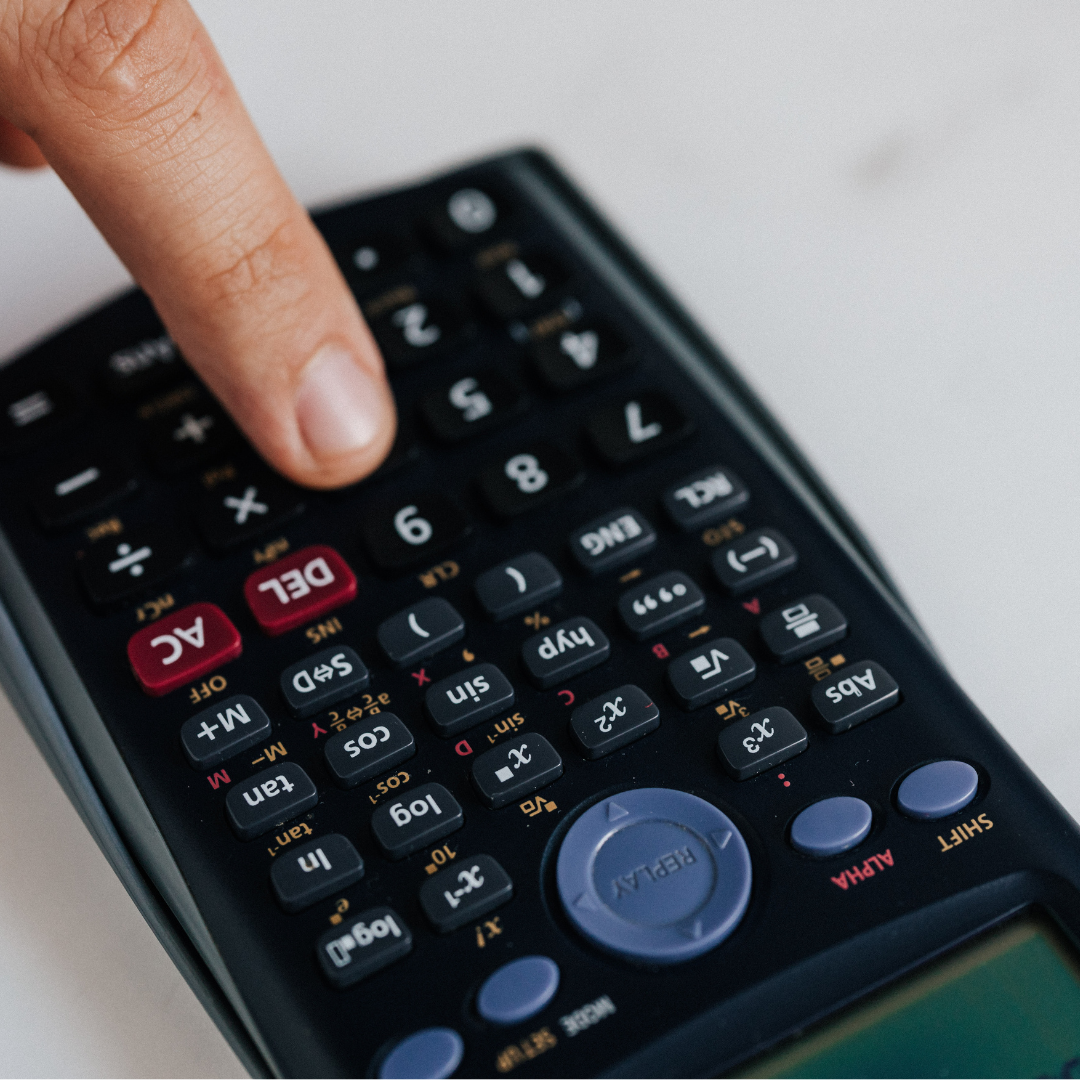 A close-up of a hand pressing buttons on a scientific calculator, showing numbered keys and mathematical function buttons against a light background.