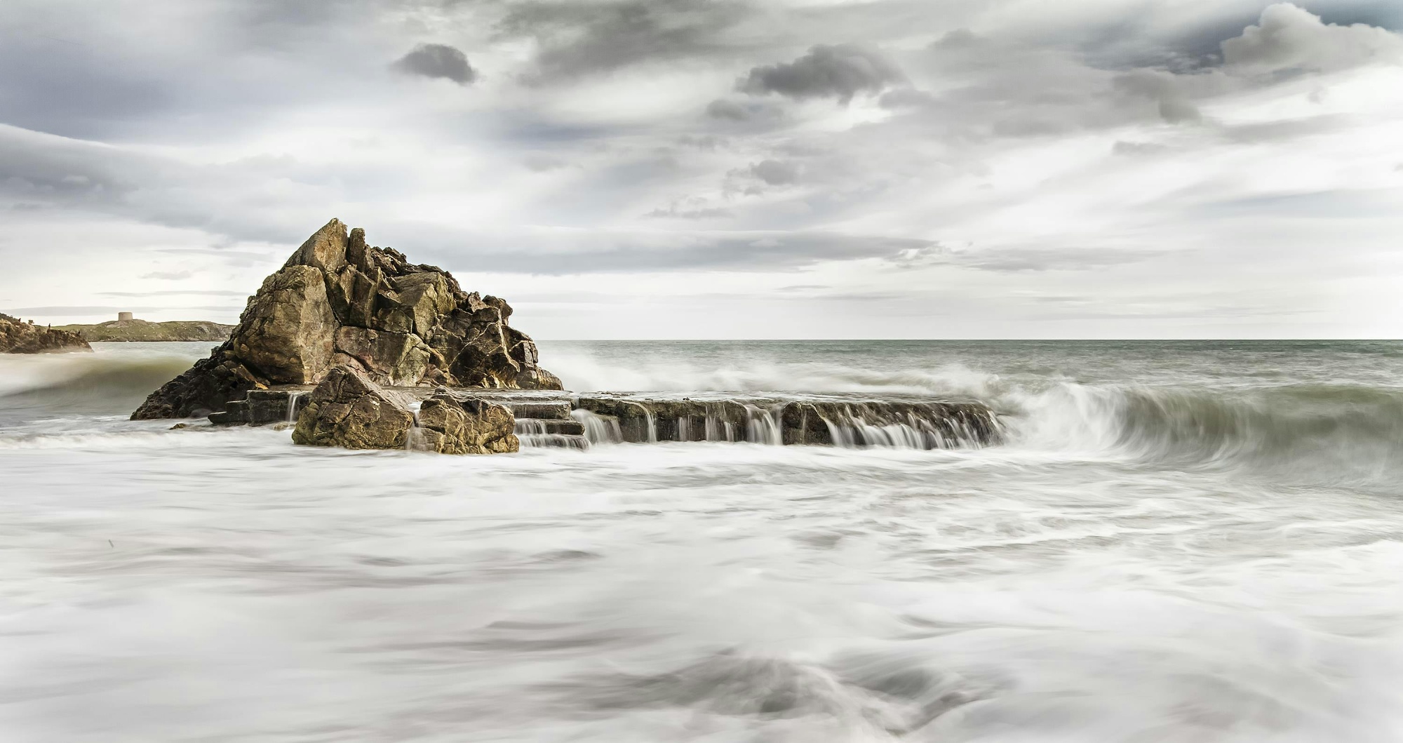 Image shows a dramatic photograph of rocks at Killiney Beach
