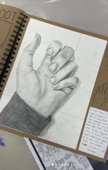 A detailed pencil drawing of a hand in a sketchbook, showing careful shading, proportion, and observation work.