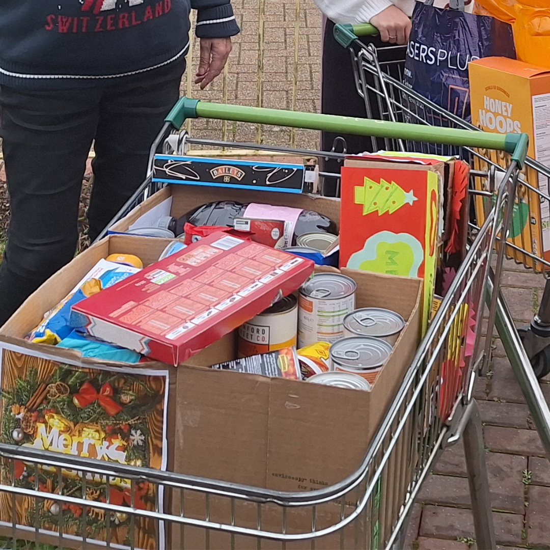 This image shows a trolley filled with cardboard boxes that contain tinned goods and other non-perishable items. 