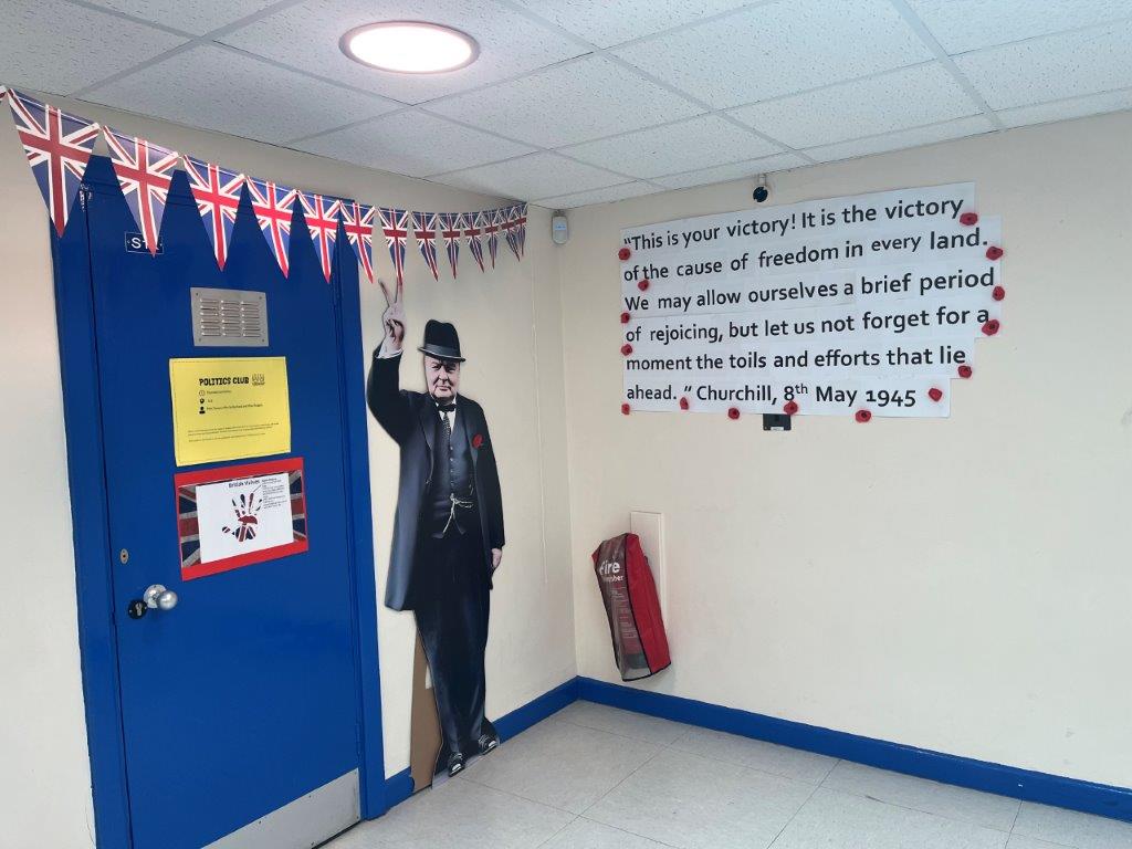 Image shows a life size photograph of Winston Churchill and words from his speech, with more Union Jack bunting at the end of the S-block Humanities corridor.