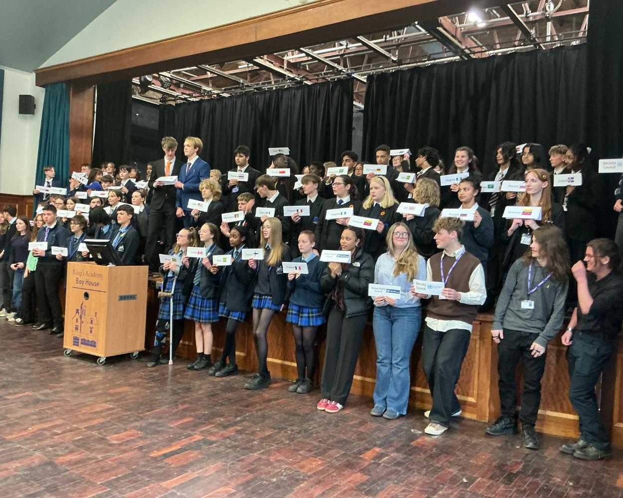 Image shows all the pupils that took part in the Model UN on the stage - this picture is taken from the side nearest the Swanmore Pupils