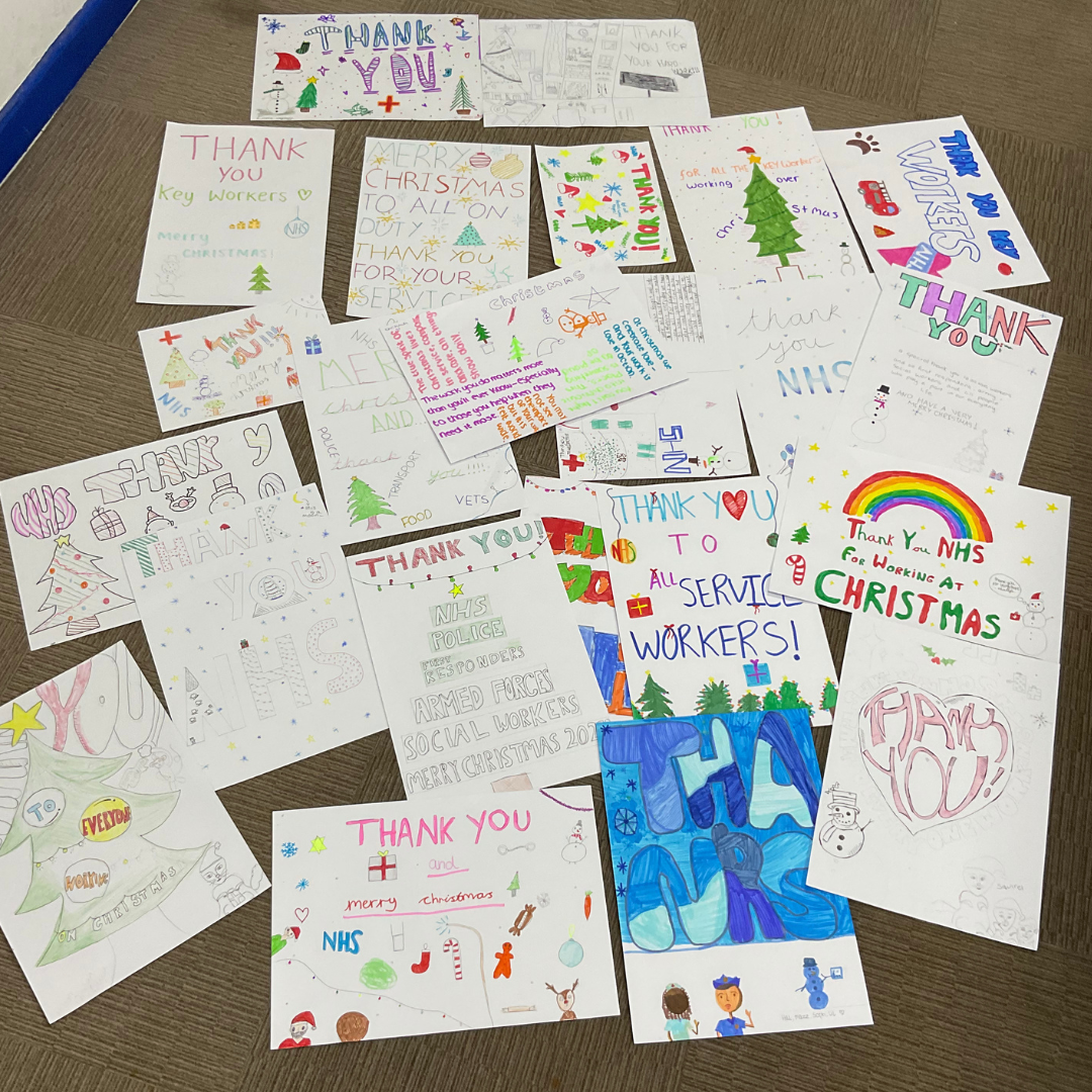 This image shows a variety of hand-made posters on the ground. The posters are Christmas themed and are thanking community workers for working over Christmas. 