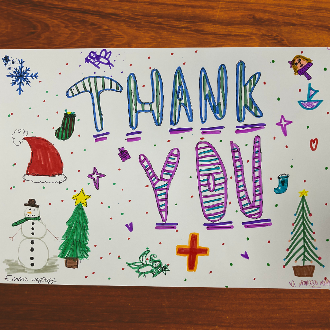 This image shows a hand-made poster with the words "Thank You" in the centre in stripey blue and purple text. The poster also has drawn images of a snowman two Christmas trees a santa had a snow flake a stocking and other Christmas imagery. 