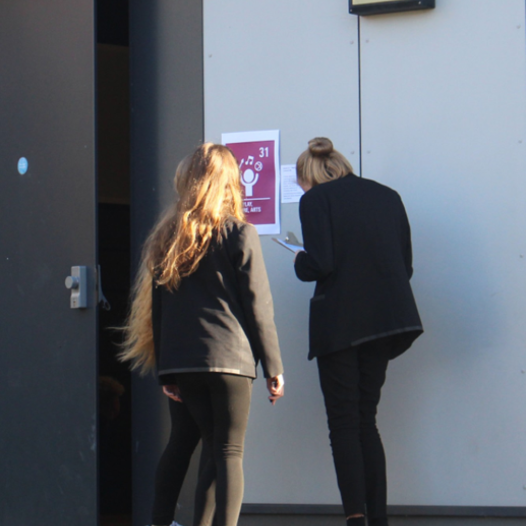 Pupil completing a Rights Respecting Schools activity outside a classroom displaying an Article 31 poster about leisure, play and the arts.