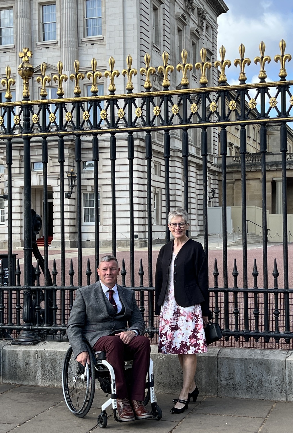 Two guests posing outside Buckingham Palace during the Duke of Edinburgh’s Award 70th anniversary celebration.