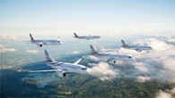 Image shows a group of 5 aeroplanes in flight over countryside.