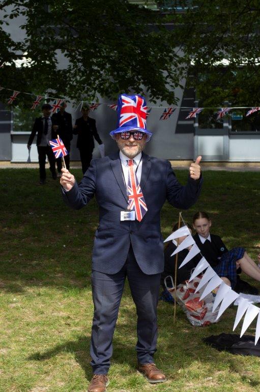 Image shows Mr Valentine dressed in a blue suit with a Union Jack tie, top hat, glasses and flag.
