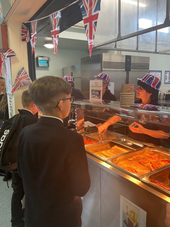 Image shows pupils ordering food from the Swan Cafe staff, who were dressed union jack hats, and played 1940s music throughout service