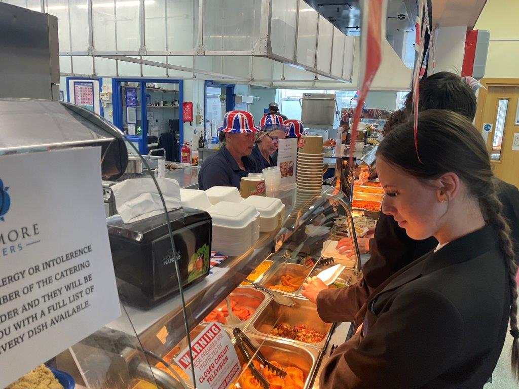 Image shows pupils ordering from our fantastic kitchen staff who dressed up for the day.
