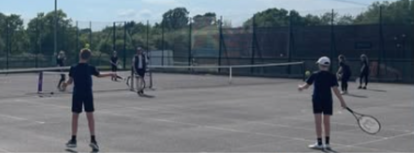 image shows pupils playing tennis in the sunshine during KS3 tennis club