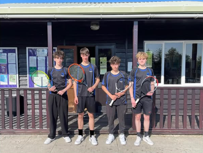 Four Year 9 and 10 boys from Swanmore College standing outside a clubhouse holding tennis rackets before a tennis fixture.