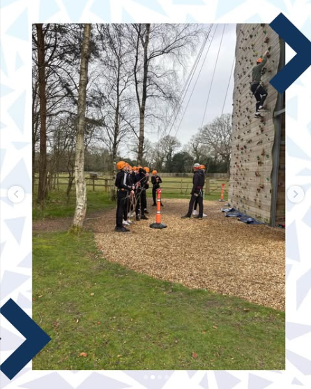 Image shows a group of pupils with orange safety helmets on, getting ready to climb a wall on the tower. One pupil is halfway up.