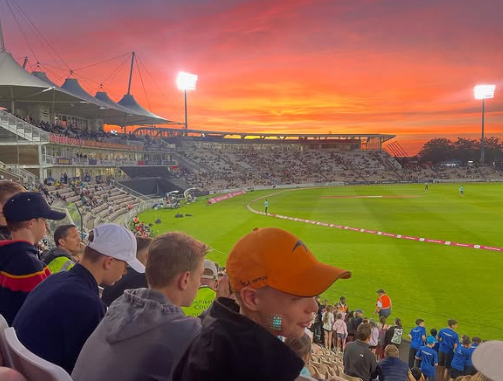 Image shows pupils watching the T20 match at sunset