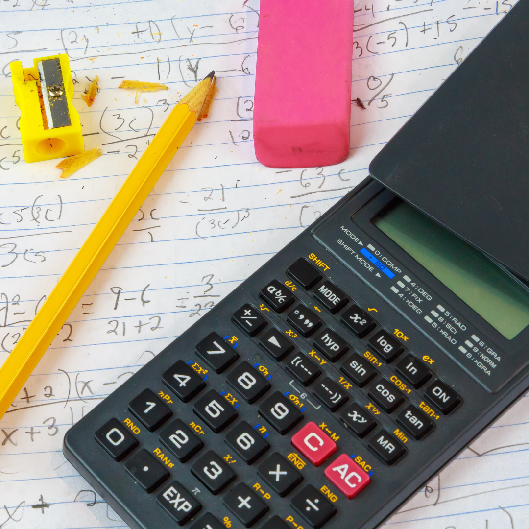 Image shows an exercise book page covered in maths workings, a pencil sharpener, pencil, eraser and calculator